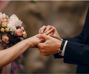 Close-up of a bride and groom holding hands during wedding ceremony.